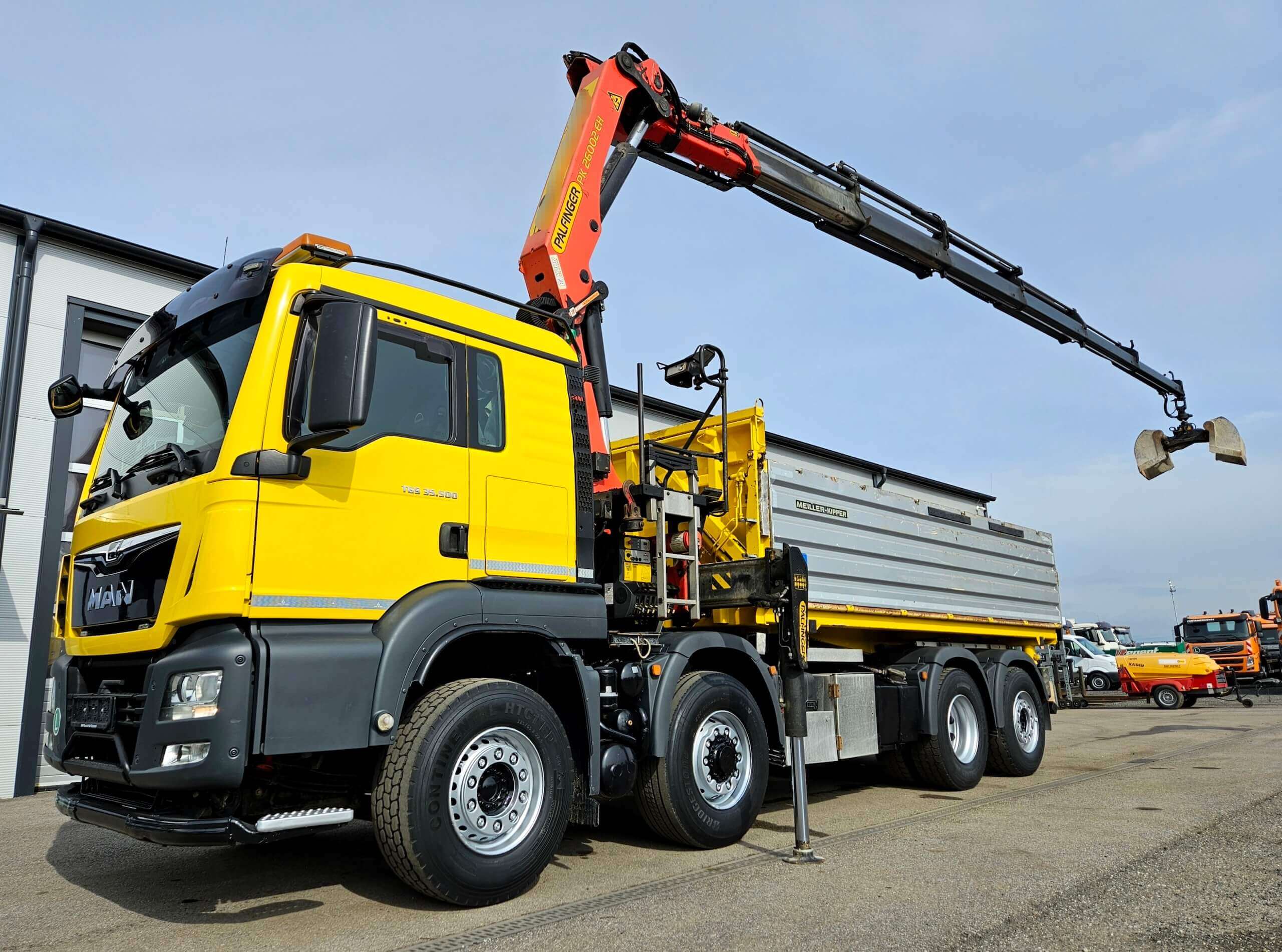 Gelber Lkw mit Kran auf Baustelle, bereit für schwere Hebearbeiten im Industrieeinsatz.