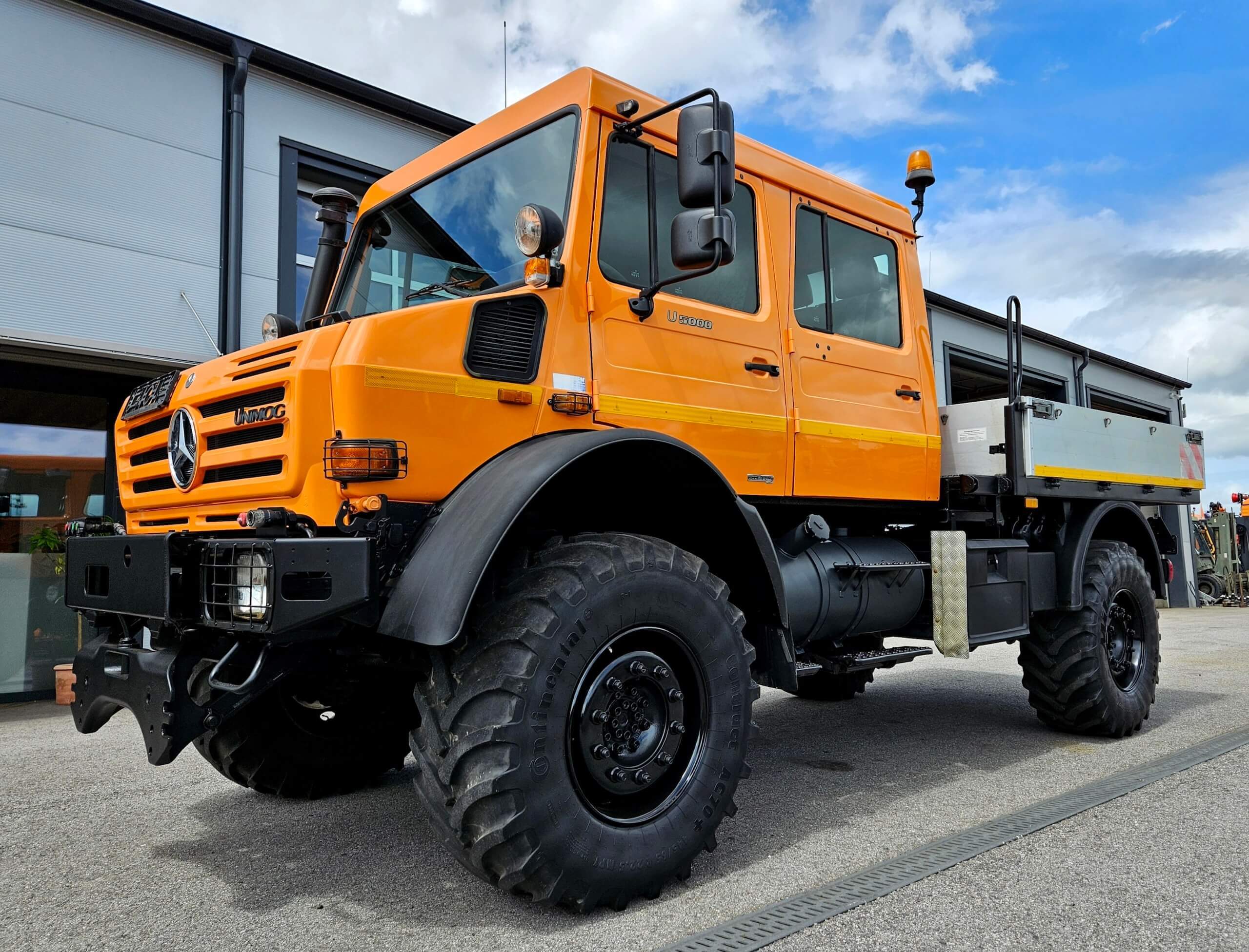 Orange Mercedes Unimog U 5300 mit robusten Geländereifen, ideal für Offroad-Einsätze und schwere Arbeiten.